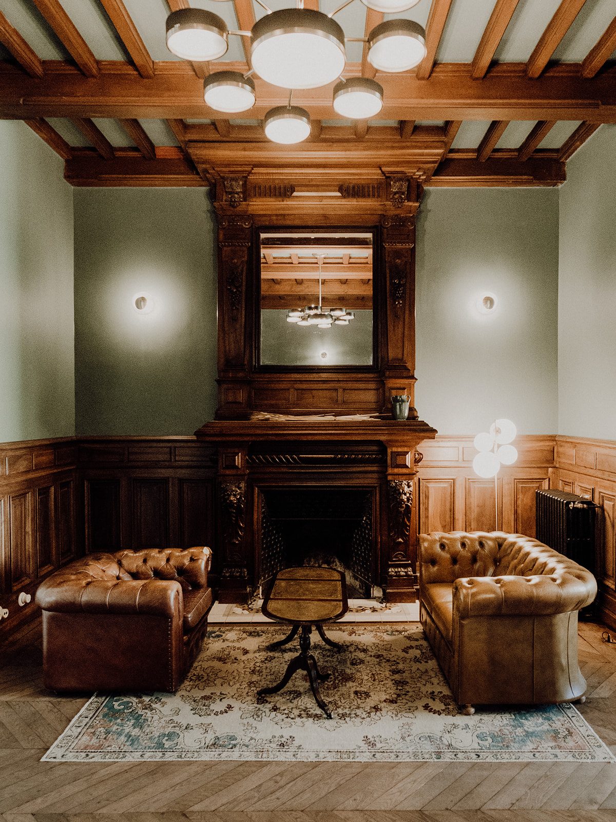 Salon d'accueil avec cheminée d'origine, boiseries et fauteuils Chesterfield